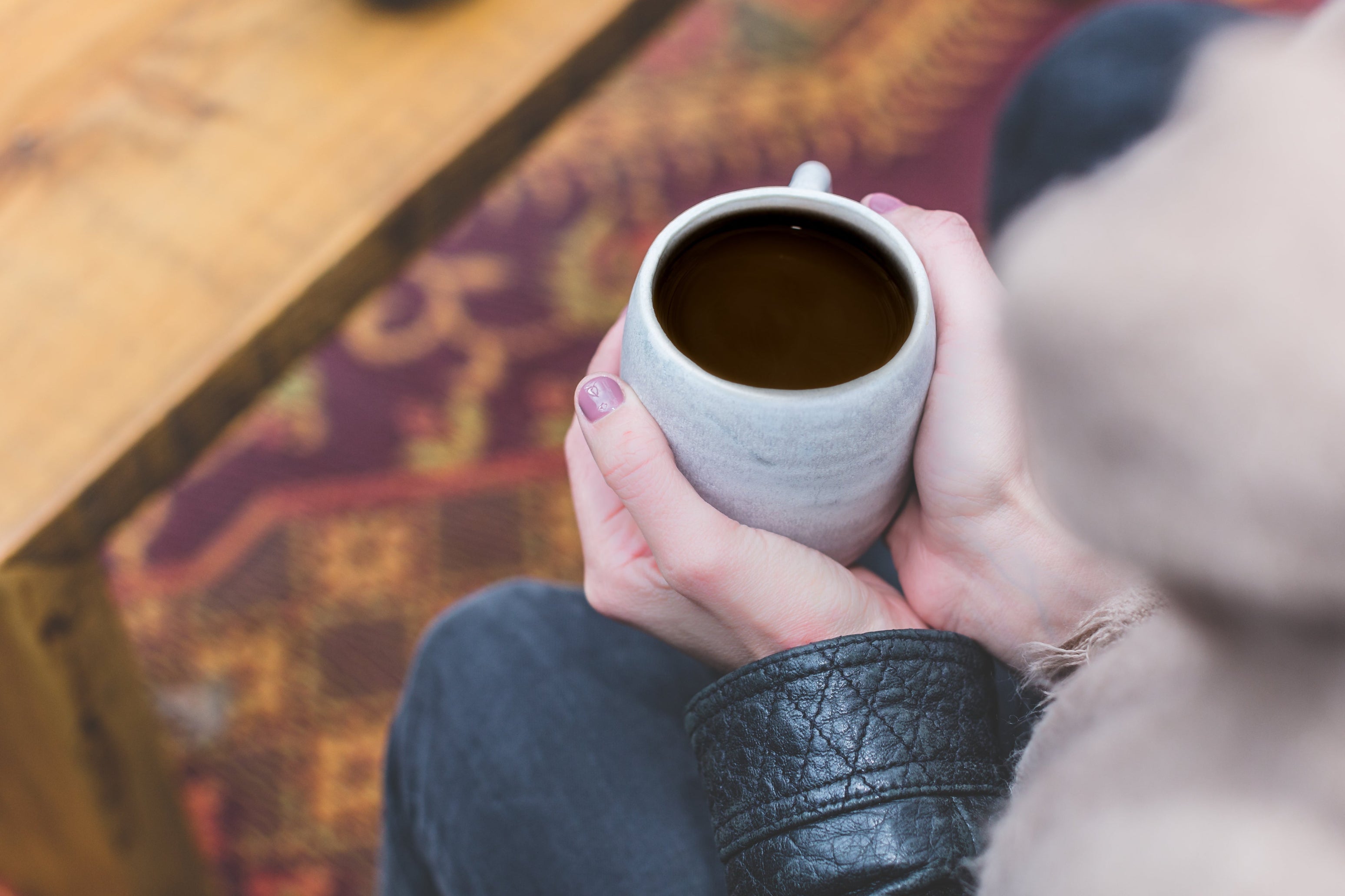 Person holding a mug of coffee with a blurred background